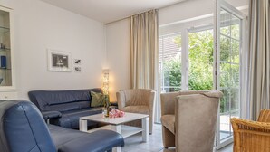 A modern living room with a sofa, armchairs, and a coffee table. - Timeless and elegant: the semi-detached house impresses with both its brightness (Carolinensiel)