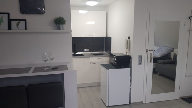 Espaço compacto com cozinha americana, área de refeições e sala de estar com sofá.