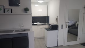 A compact living space with a kitchenette, a dining area, and a seating area with a sofa. - Unique Airport-Fair (Steinenbronn)