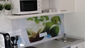 Uma cozinha compacta com armários brancos, micro-ondas, pia e lava-louças.