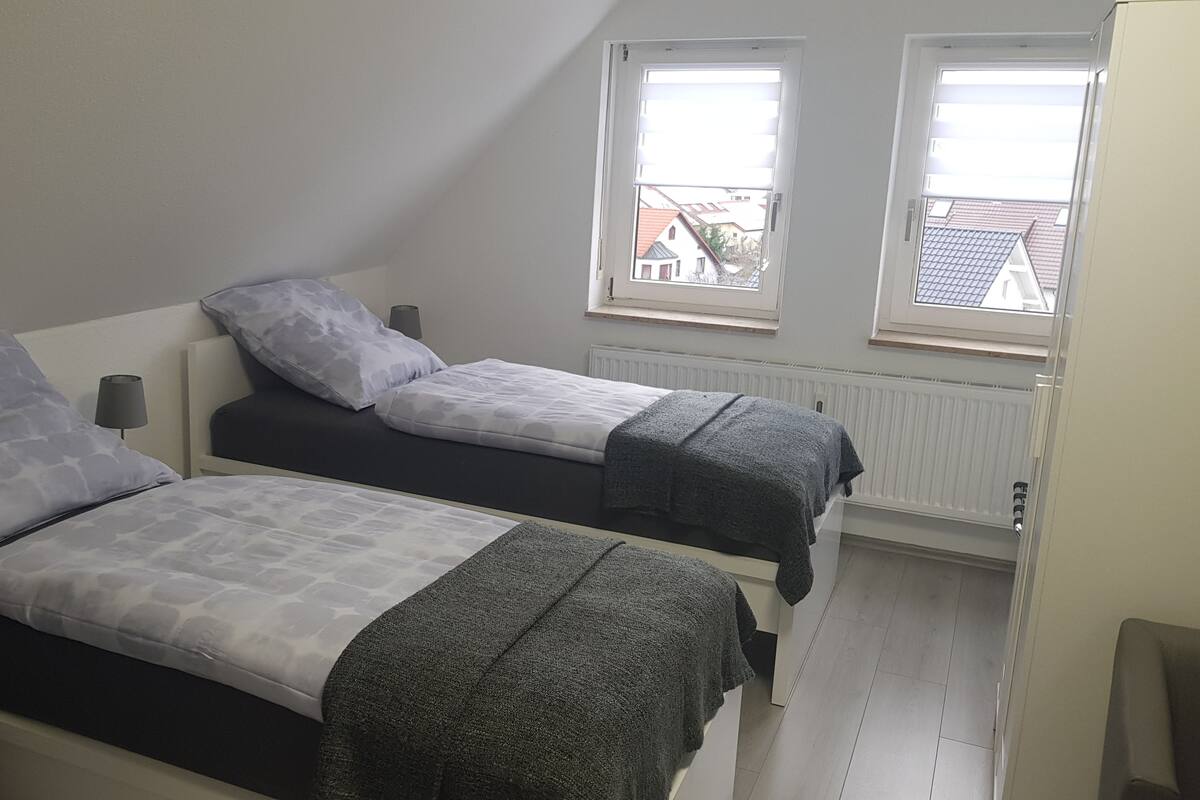 A twin room with two single beds, a window, and a radiator.
