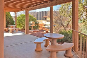 An outdoor patio with terracotta tables and benches, a pergola overhead, and a view of a mountainous landscape. - Red Rock Escape - prime Sedona condo near trails, restaurants & shopping! (Sedona)