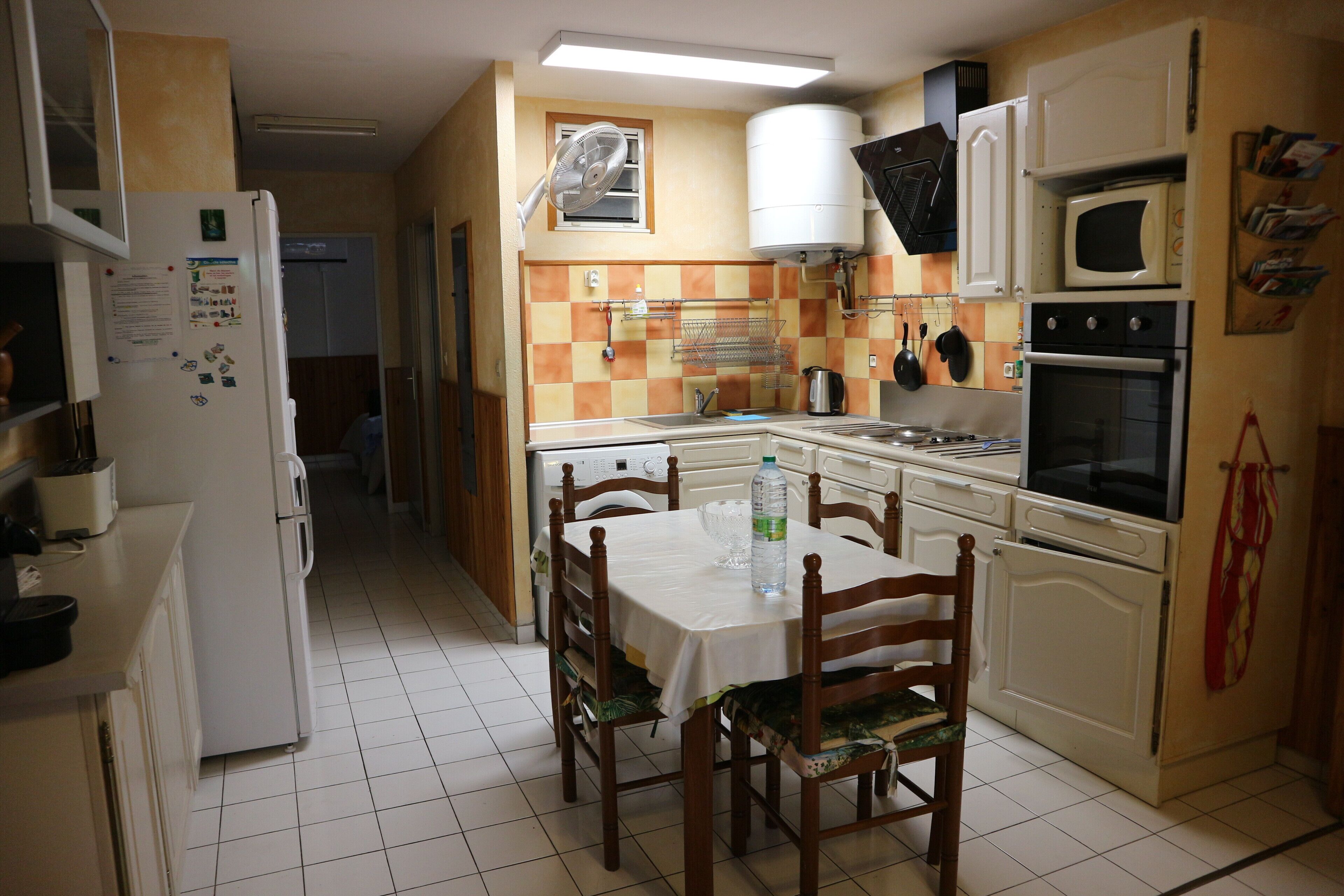 Eine kompakte Küche mit Esstisch, Stühlen, Kühlschrank, Mikrowelle und Herd.
