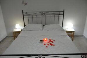 A neatly made bed with a single lit candle and rose petals on the bedspread. - B&B Vecchio Porto (Catania)