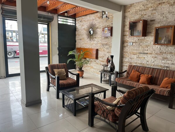 Un hall con pared de ladrillo, un espejo grande, un sofá, dos sillones y una mesa de centro.