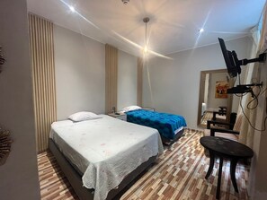 A bedroom with two beds, a TV mounted on the wall, and a small table.
