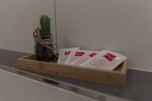 A wooden tray with a small cactus and several white packets on a countertop. - Mey Hotel (Osnabrueck)