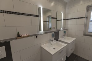 A modern bathroom with two sinks, a large mirror, and a small window. - Mey Hotel (Osnabrueck)