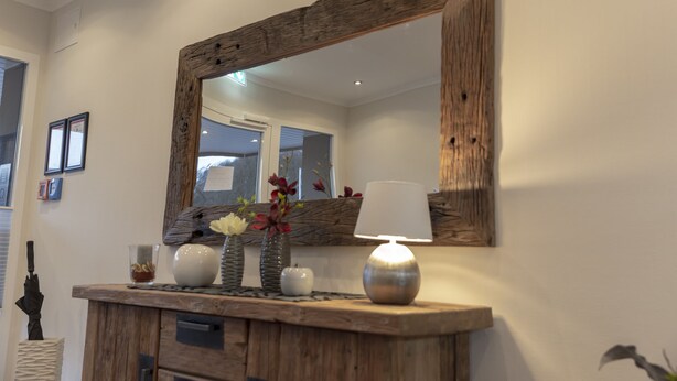 A wooden console table with a mirror, a lamp, and decorative items including vases and flowers.