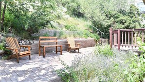 An outdoor seating area with wooden chairs and a bench, surrounded by greenery and a stone wall. - Garden Home: Private Home Downtown Durango (Durango)