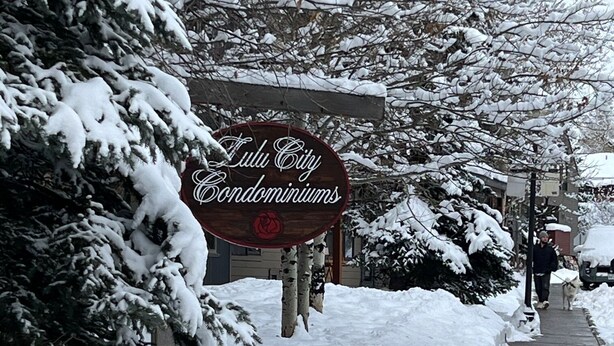 Uma rua coberta de neve com um letreiro para 'Lulu City Condominiums'.