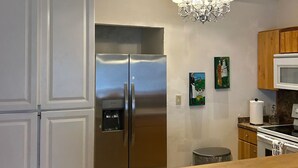 Cozinha moderna com eletrodomésticos de aço inoxidável, bancada de madeira e lustre.
