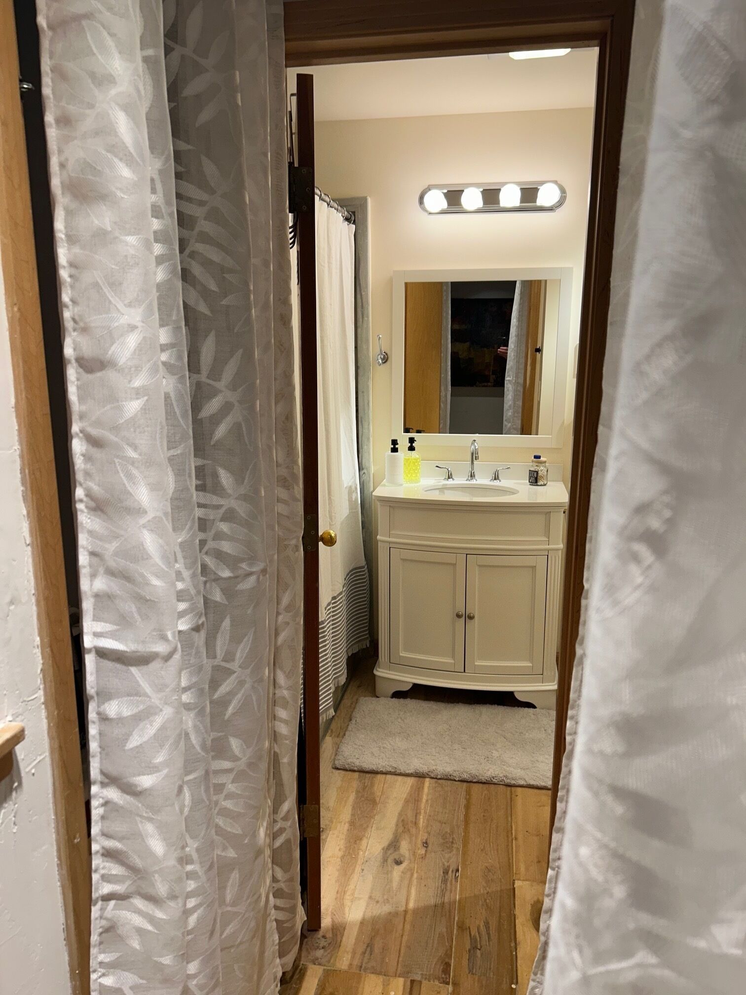 Une salle de bain avec un meuble-lavabo blanc, un miroir et un miroir de coiffeuse avec éclairage intégré.