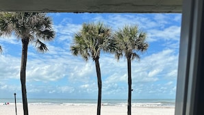 Vista de una playa con palmeras y un área de estar exterior blanca.