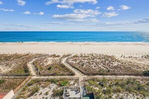 A beach with a clear sky, sandy shore, and a wooden boardwalk leading to a building.