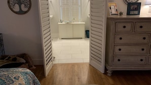 Un dormitorio con cama, cómoda y baño con ventana e inodoro.