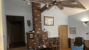 A living room with a fireplace, a ceiling fan, and a blue armchair.