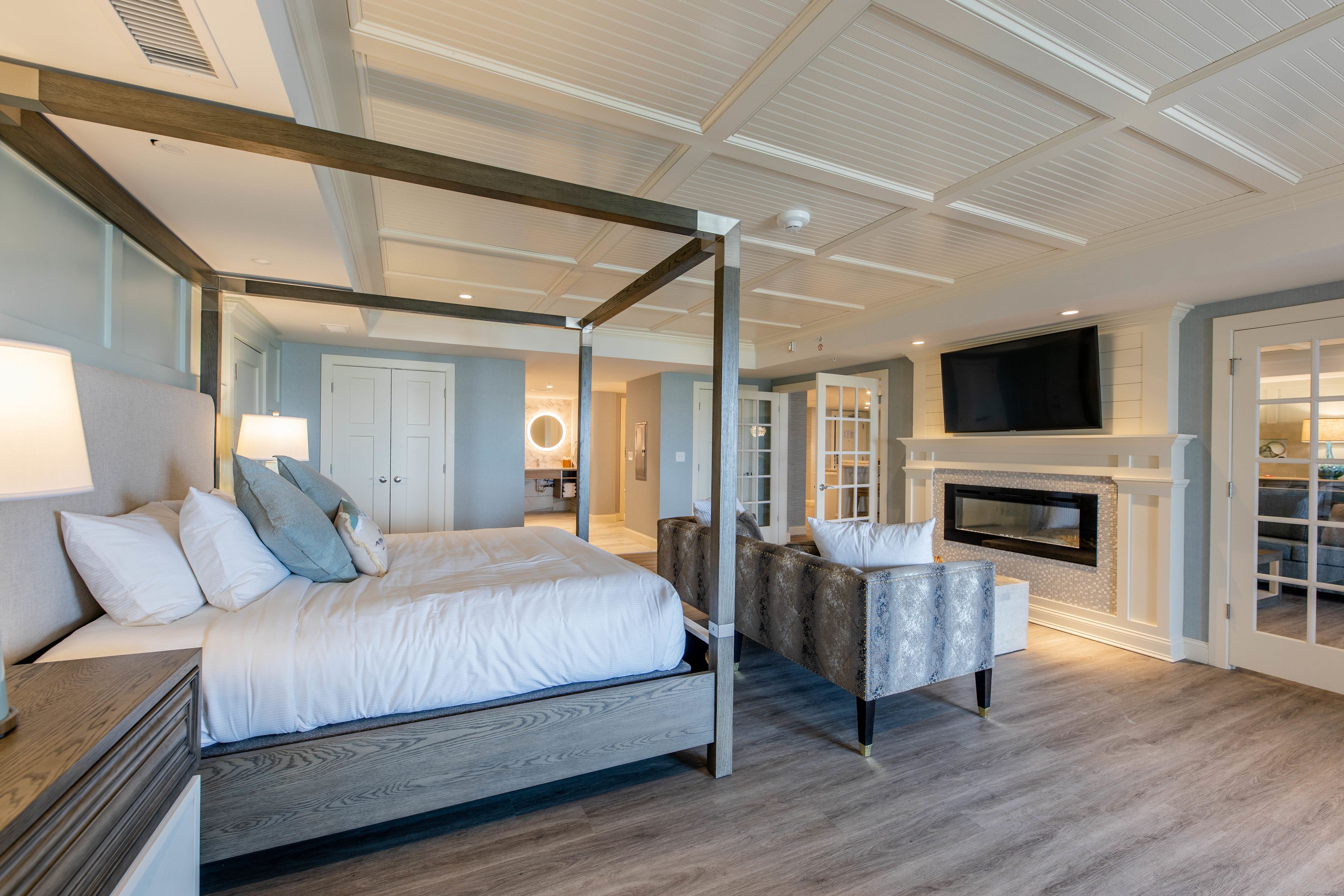 Un dormitorio moderno con cama con dosel, chimenea y televisión.