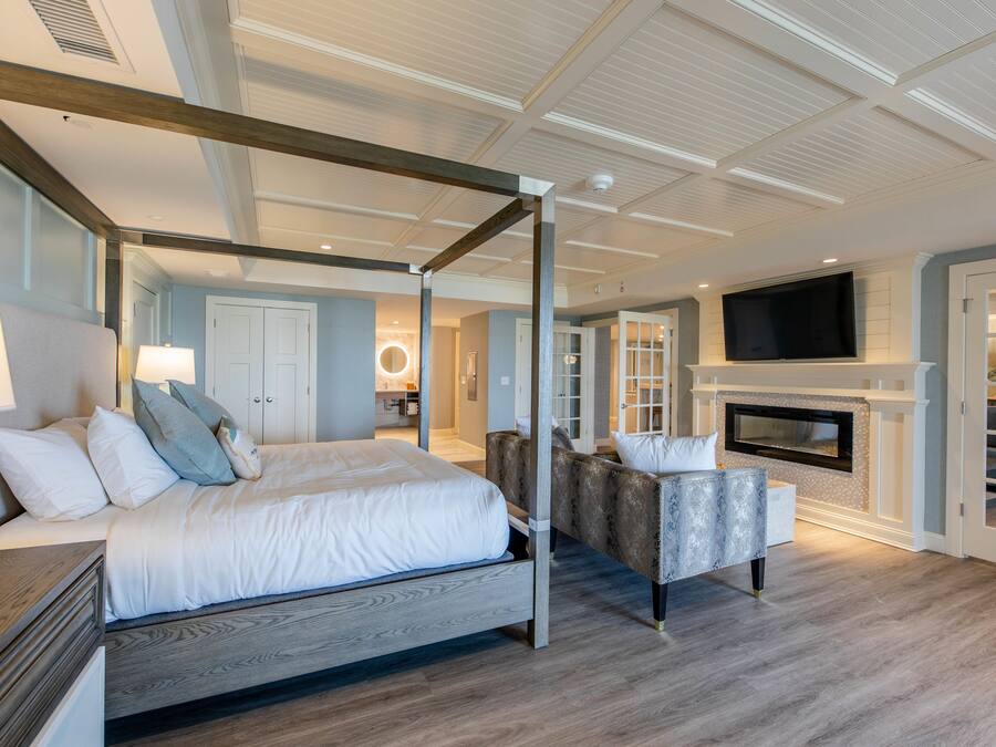 Un dormitorio moderno con cama con dosel, chimenea y televisión.