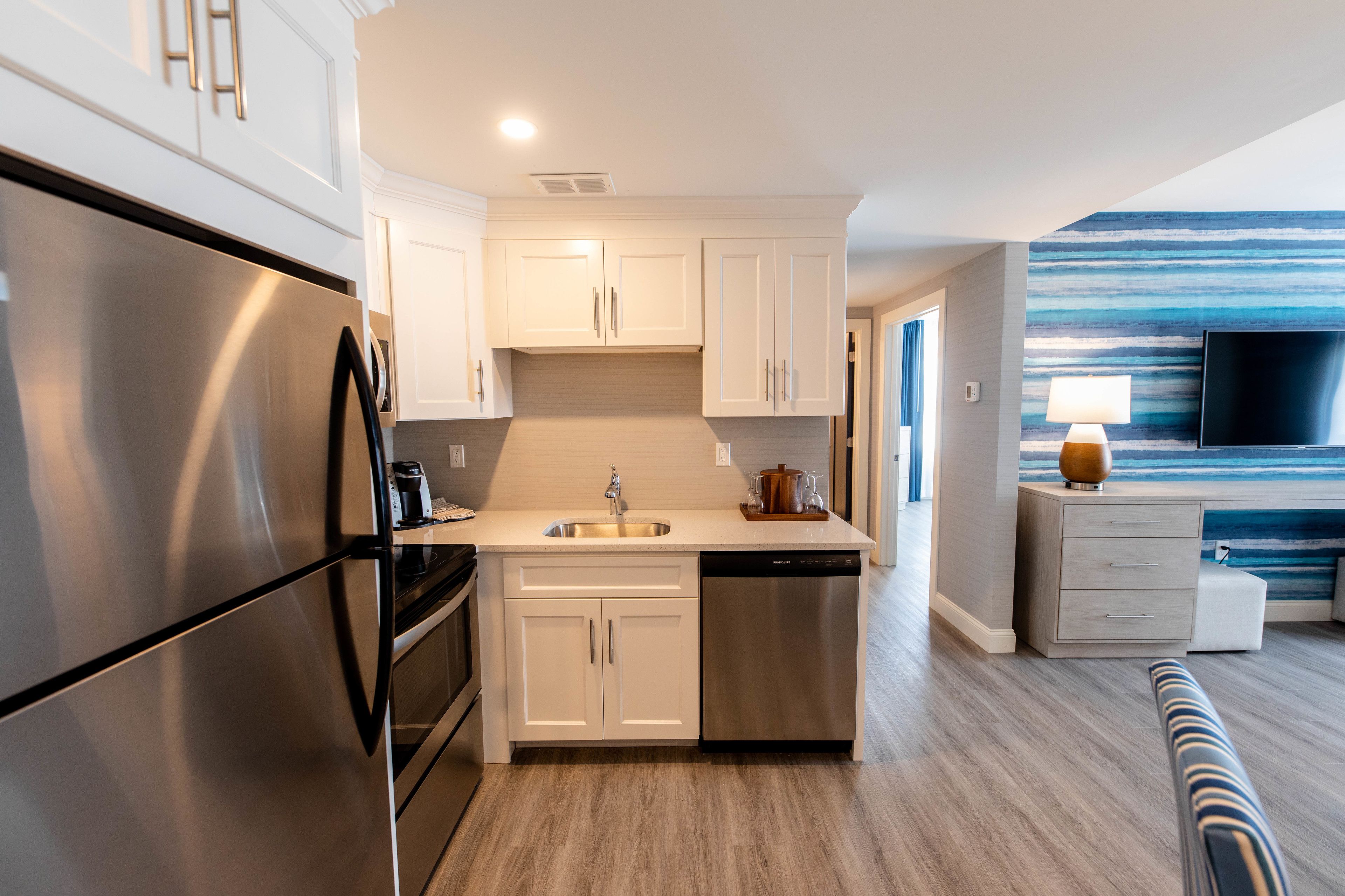 A modern kitchen with stainless steel appliances, white cabinetry, and a built-in dishwasher.