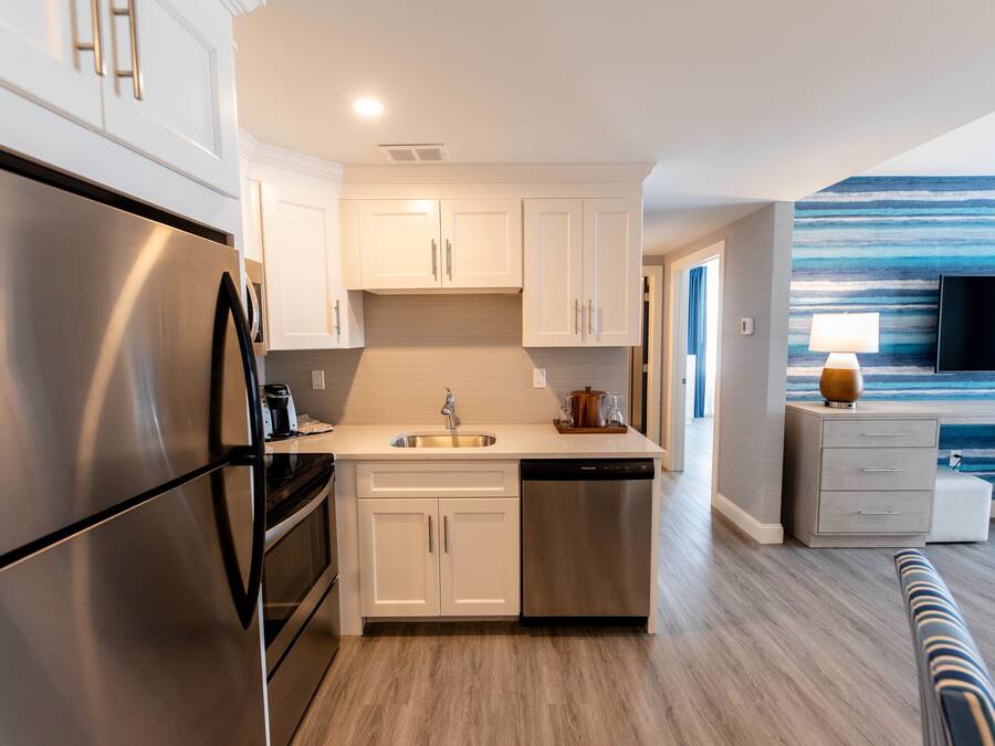 A modern kitchen with stainless steel appliances, white cabinetry, and a built-in dishwasher.