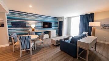 A modern living room with a striped wall, a flat-screen TV, a sofa, a dining table with striped chairs, and a lamp.