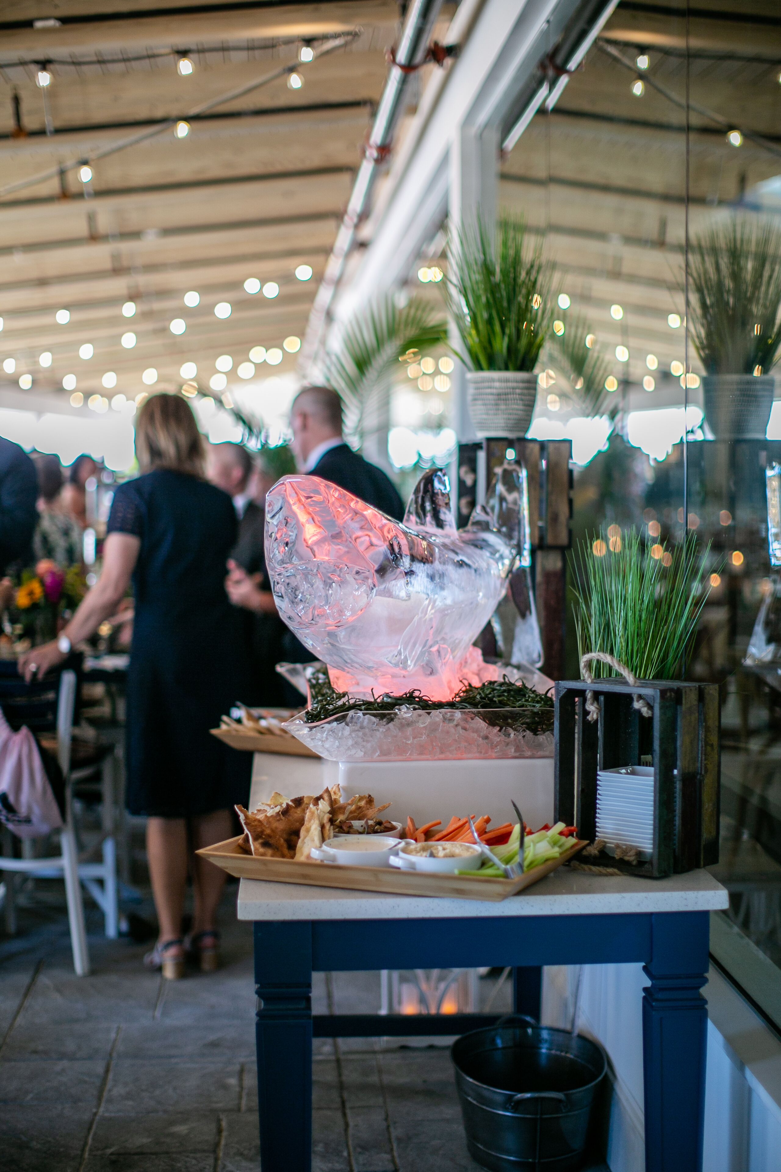 A table with a decorative centerpiece, a potted plant, and a tray of food.