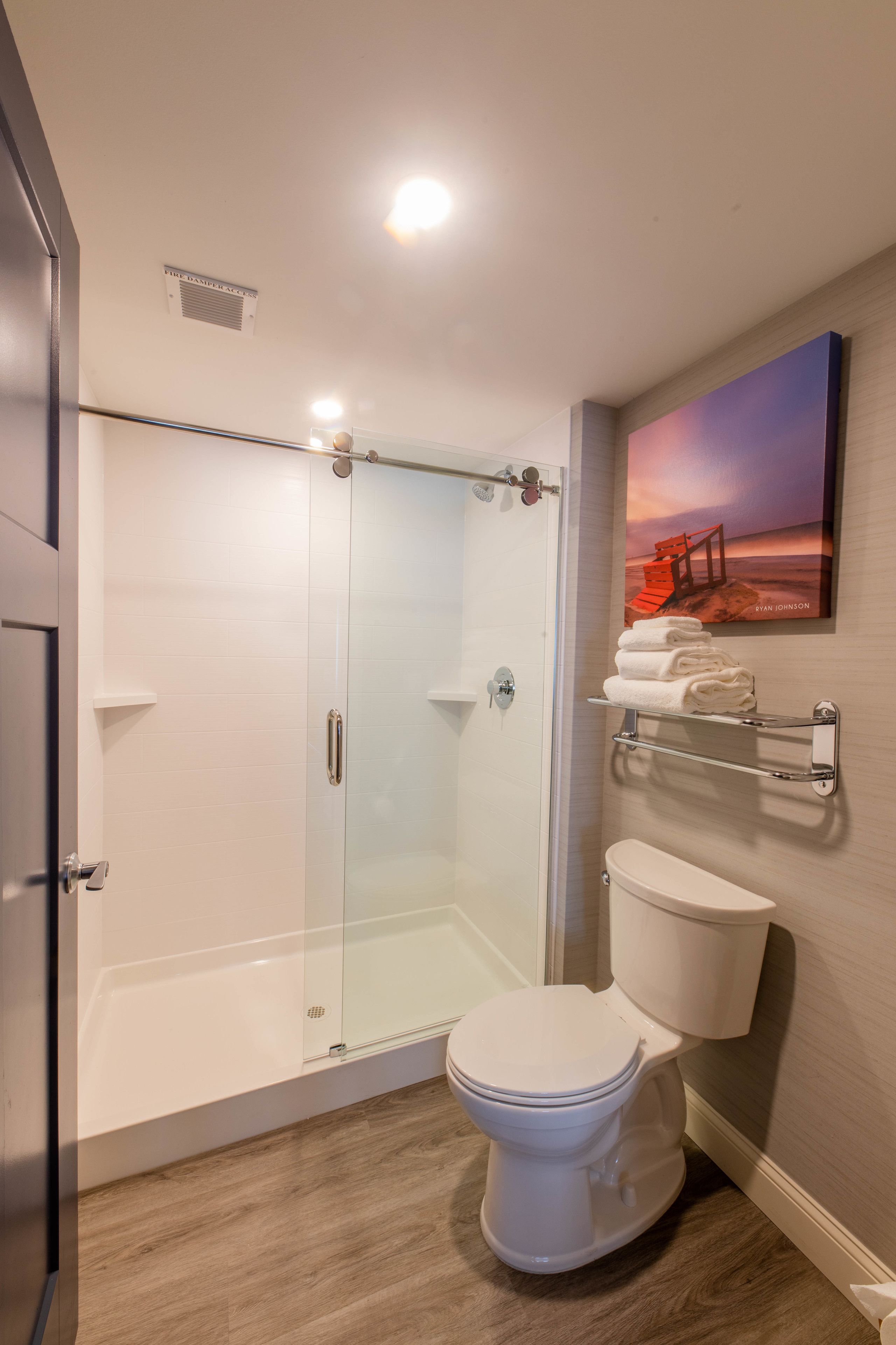 Un baño moderno con ducha acristalada, inodoro y toallero.
