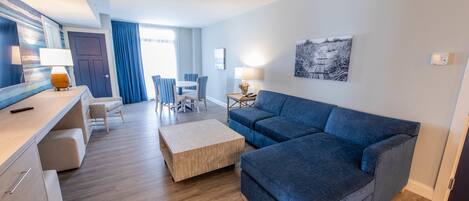 A modern living room with a blue sofa, wooden coffee table, and striped chairs.