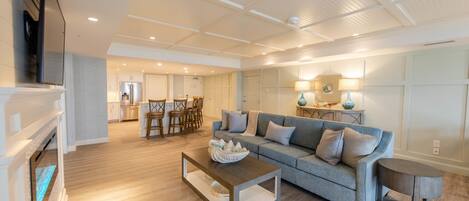 A spacious living room with a grey sofa, a coffee table, and a fireplace.