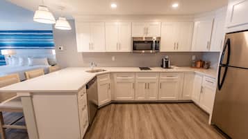 Una cocina moderna con armarios blancos, un refrigerador de acero inoxidable y un microondas integrado.