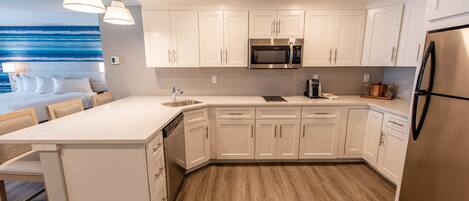 A modern kitchen with white cabinetry, a stainless steel refrigerator, and a built-in microwave.