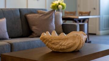 A modern living room with a wooden coffee table, a grey sofa, and a decorative wall piece.