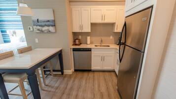 A modern kitchen with white cabinets, a stainless steel refrigerator, and a dishwasher.