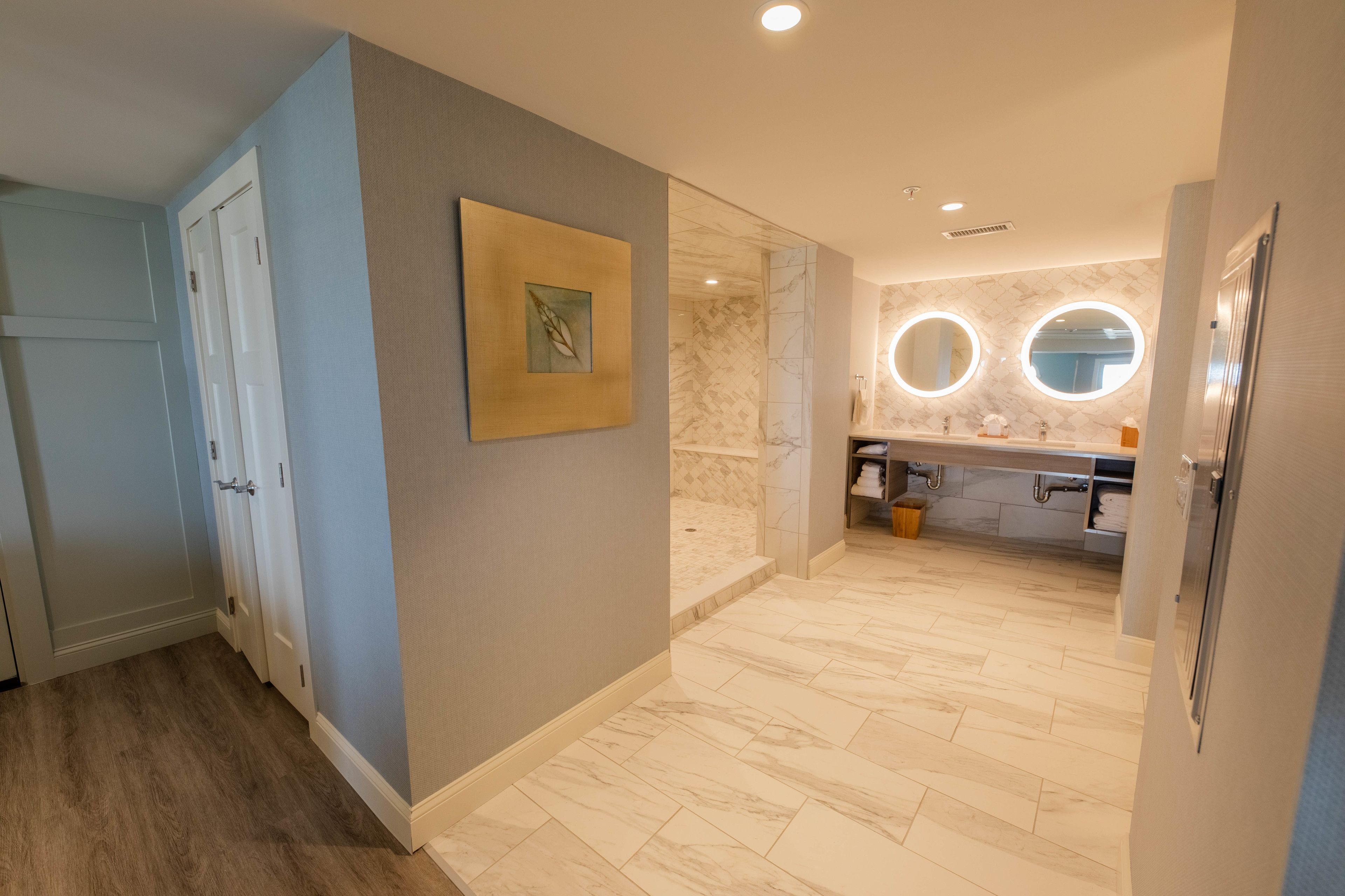 Un baño moderno con suelo de mármol, un lavabo con espejo y una obra de arte enmarcada en la pared.