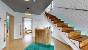 A modern interior with a staircase, wooden floor, and a view of a lighthouse.