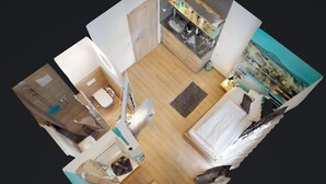 A 3D model of a hotel room with a bed, a desk, a chair, a small table, a sofa, and a bathroom.