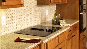 Una cocina con armarios de madera, encimera de granito, estufa integrada y una botella de vino.