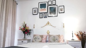 Un dormitorio ordenado con cama, mesita de noche y una pared decorada con cuadros enmarcados.