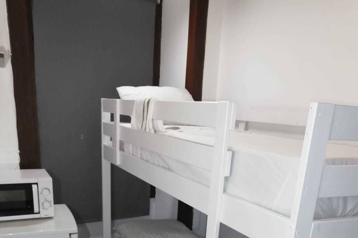 A bunk bed room with a microwave and a wooden table.