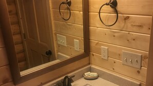 Un baño con pared de madera, un lavabo con toalla y un espejo.