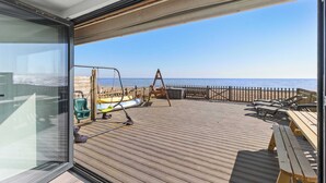 Una terrazza con vista sul mare, un'amaca e una panca di legno.