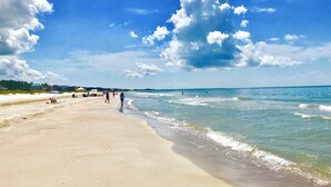 Une plage avec un ciel dégagé et des gens qui se promènent le long du rivage.