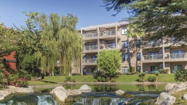 Un hôtel doté d’un bâtiment à plusieurs étages, d’un jardin aménagé et d’une petite cascade.