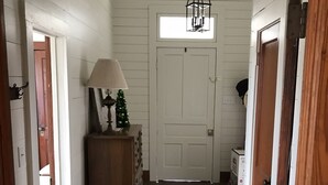 A hallway with wooden floors, a lamp, a small Christmas tree, and a cowhide rug. - Koch Ranch - Hester House  (Columbus)
