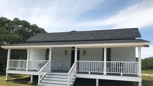A two-story house with a porch, steps, and a small garden area. - Koch Ranch - Hester House  (Columbus)
