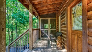 A wooden cabin with a porch, a bench, and a wooden statue.