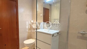 A modern bathroom with a glass shower enclosure, a white sink, and a wooden door. - 1st line beach & terrace with sea views (Cambrils)