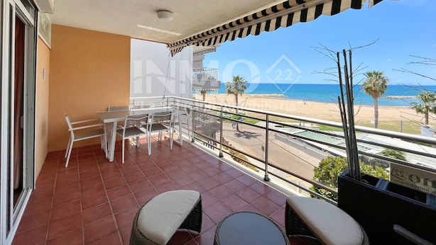 A balcony with a view of the beach, a table with chairs, and a small table with a plant. - 1st line beach & terrace with sea views (Cambrils)