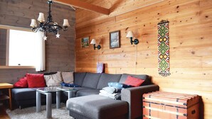 Ein gemütliches Wohnzimmer mit einem grauen Modulsofa, einem kleinen Glastisch und einer hölzernen Kommode.